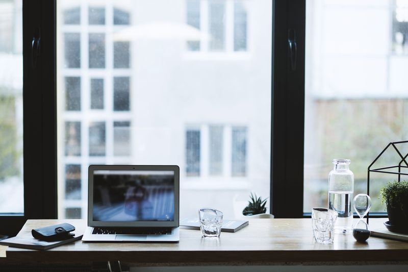 Tidy desk with an open laptop in front of a large window